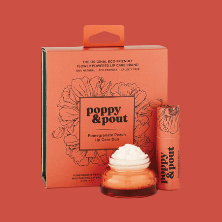 Gift set in an orange square box with black text saying, “Poppy & Pout Pomegranate Peach Lip Care Duo”. Includes and orange lip balm tube with black text and black outlined poppy flowers; small plastic container with white lid and orange lip gloss inside.
