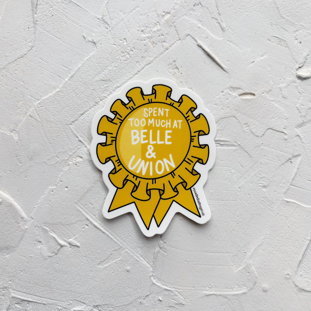 Sticker of yellow ribbon with white text, on  white textured background.