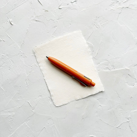 Orange pen on white textured background