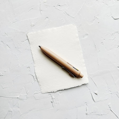 Tan pen on textured white background. 