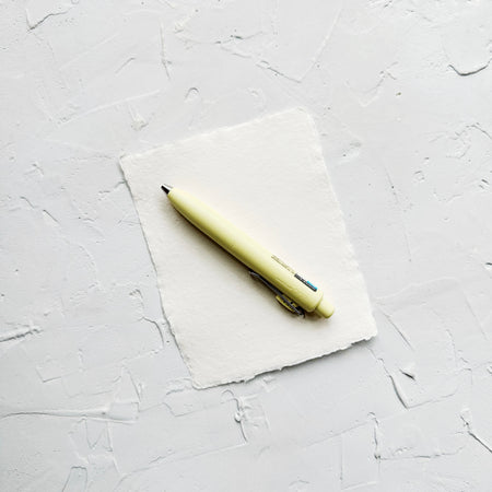 Light yellow pen on textured white background. 