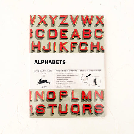 Book with letters of the alphabet on the cover. On cream textured background.