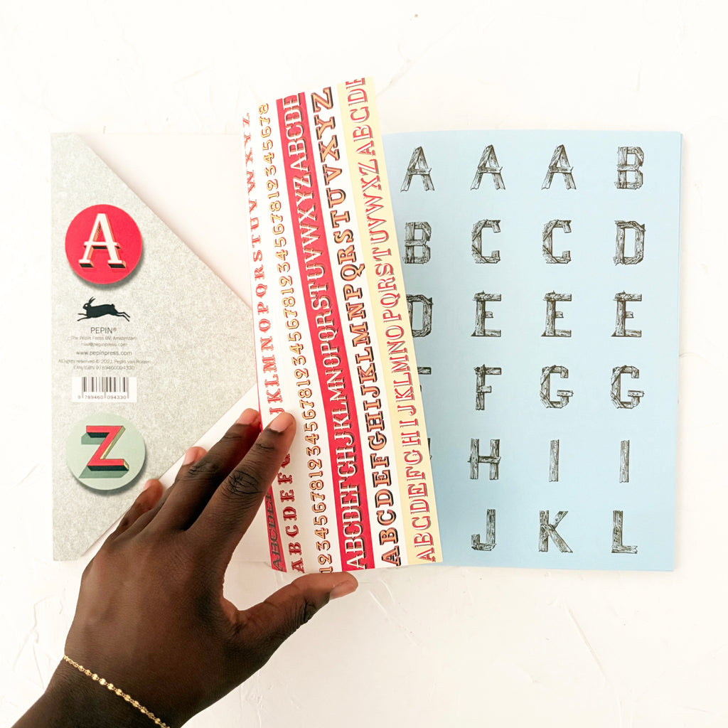 hand flipping through pages of sticker book on textured background