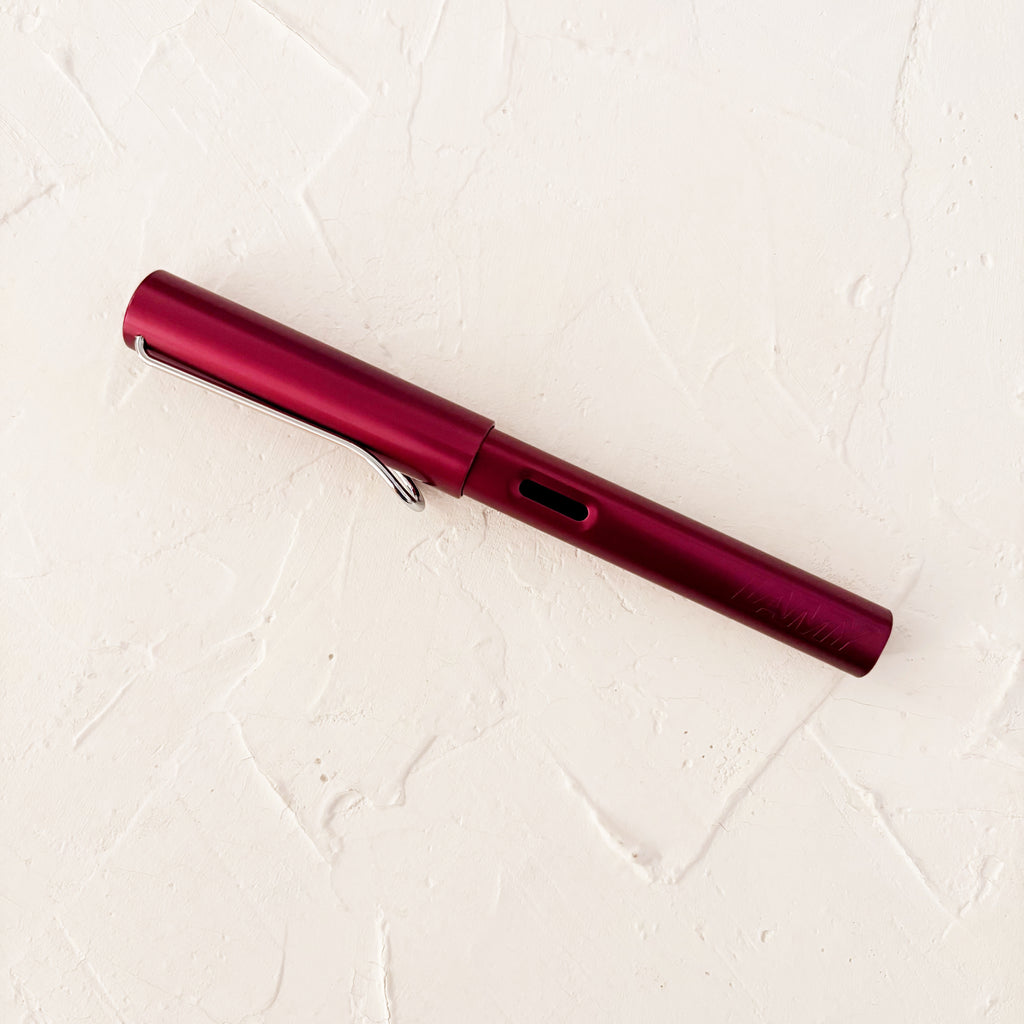 red fountain pen on textured cream fountain pen 