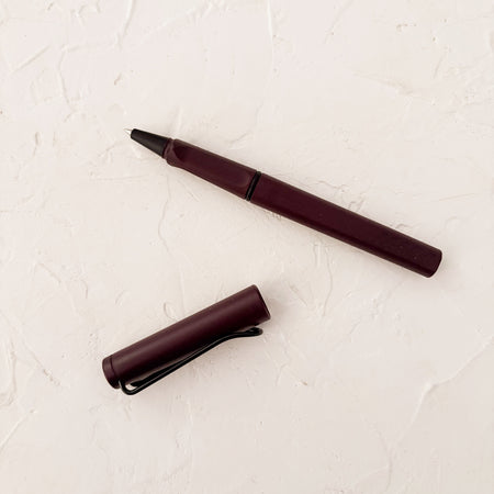 scarlet rollerball pen on white textured background. 