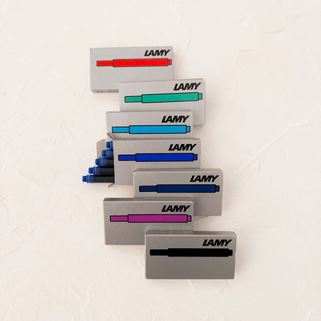 7 ink cartridge boxes stacked on top of each other, on textured background