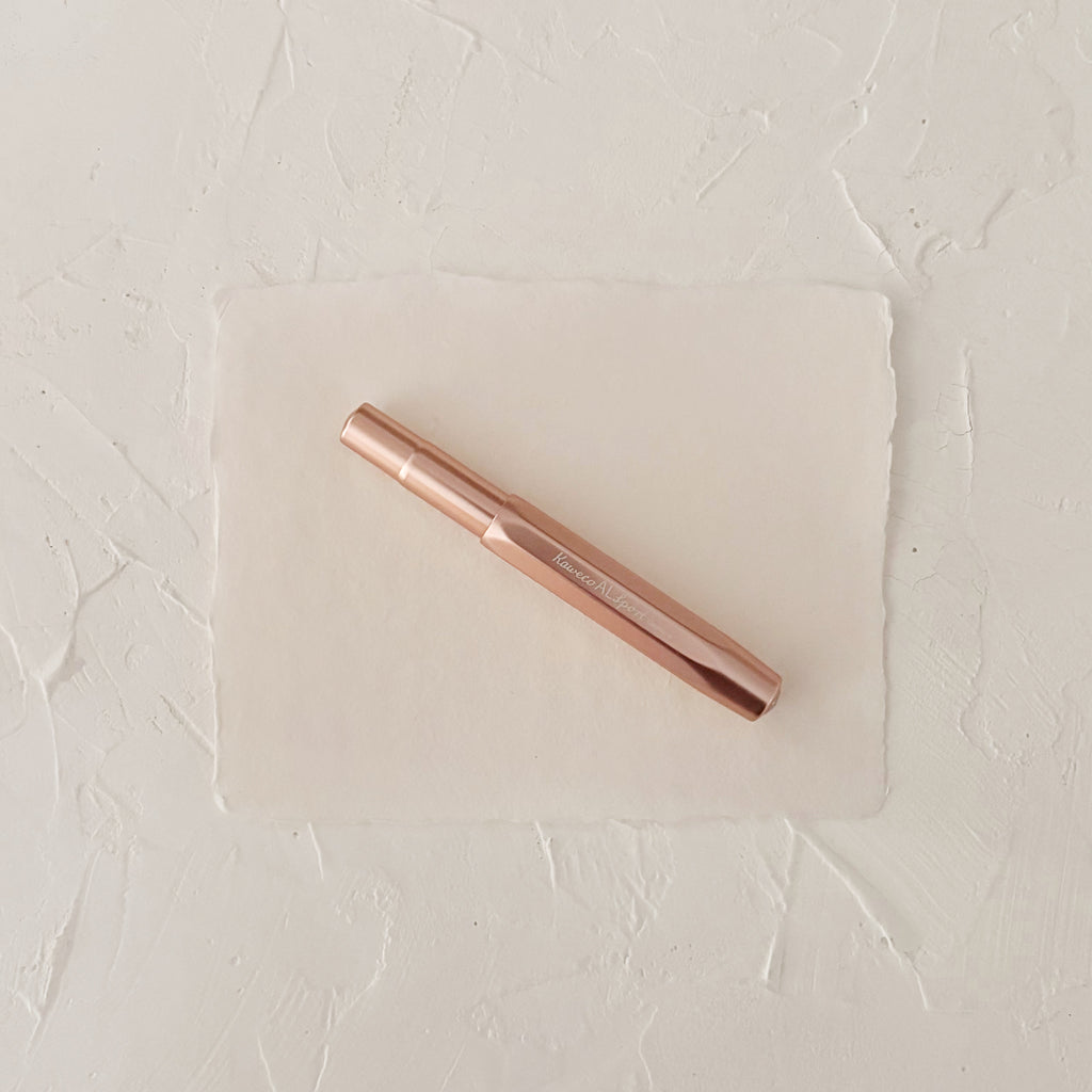 rose gold metal rollerball on textured paper