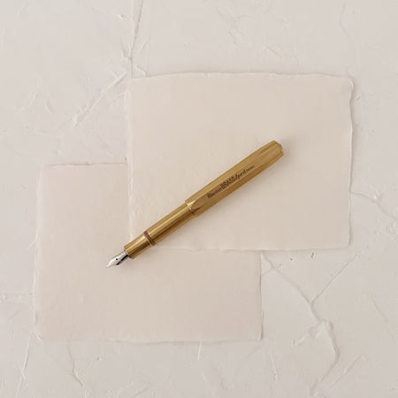 brass fountain pen on textured paper