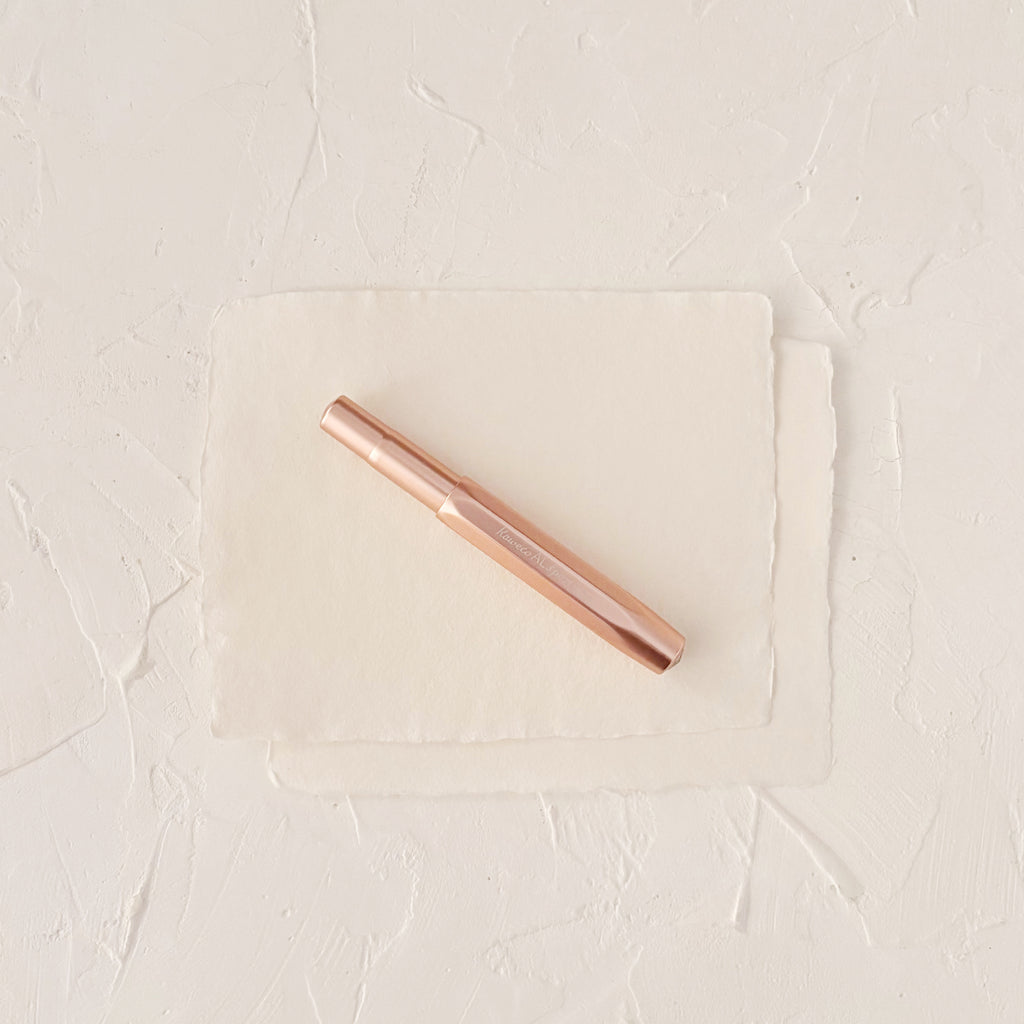 Rose gold fountain pen on textured paper
