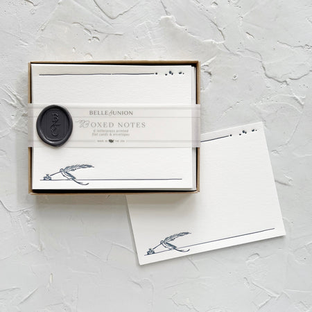 White cards with image of a blue inkwell and feather in bottom right corner and blue ink spots in top left corner.