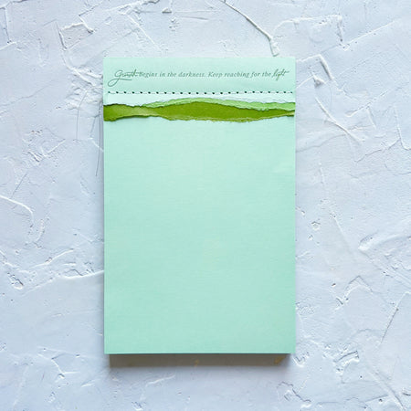 tri-color green shades notepad that says growth begins in the darkness. keep reaching for the light.