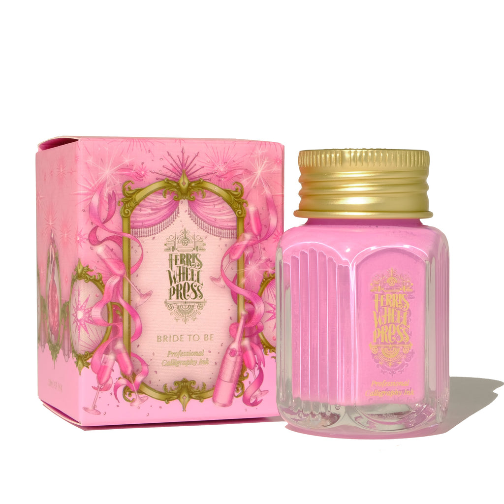 Square glass bottle with gold cover and gold text saying, "Ferris Wheel Press" with images of a ferris wheel on front of bottle. Ink is flamingo pink. Packaged in square pink box with images of ribbons, champagne and champagne glasses.