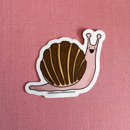Sticker in the shape of a snail with brown shell and pink body with a happy face.