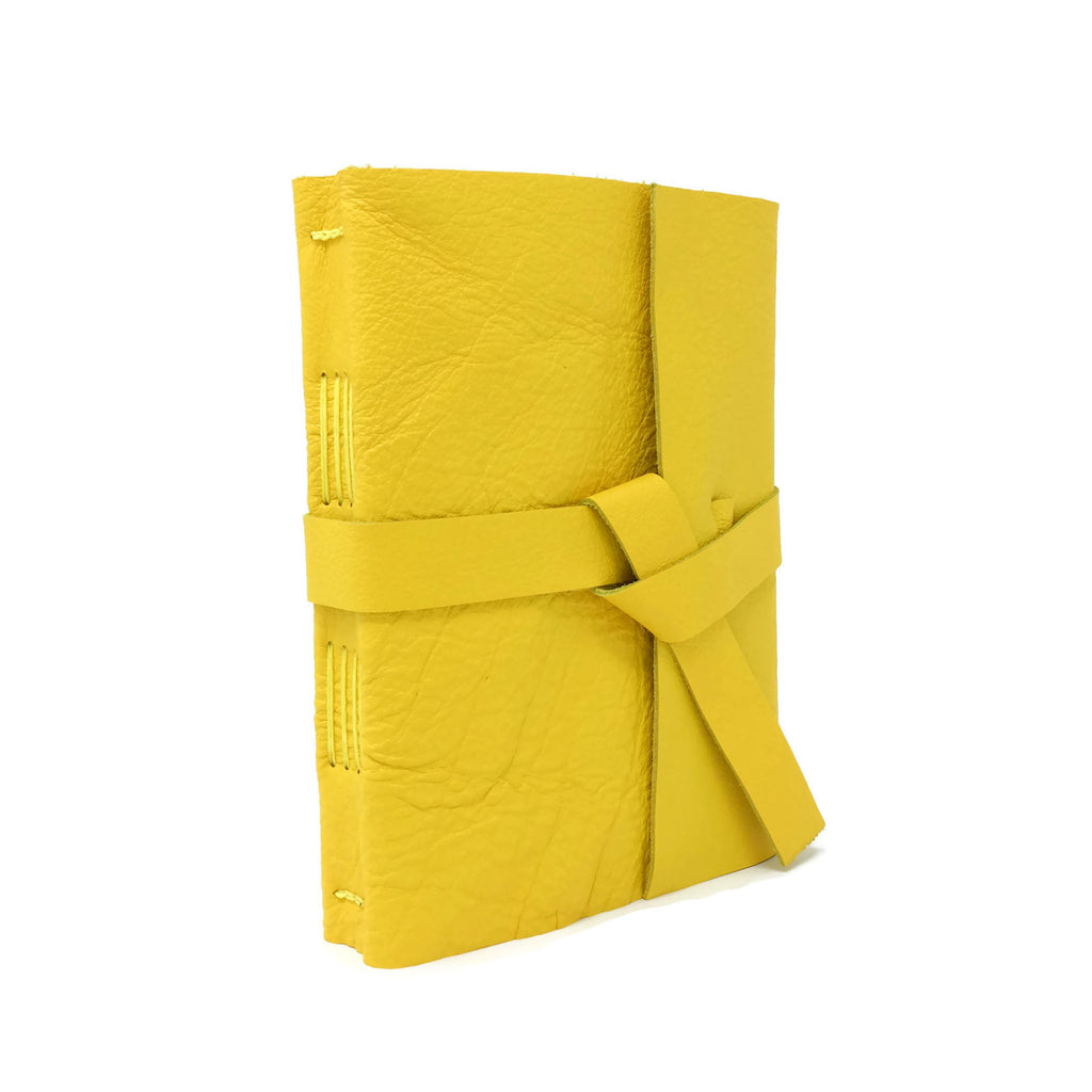 Yellow leather cover with two straps that tie together to close notebook.