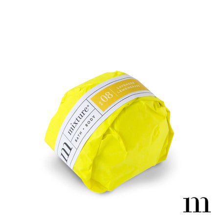 Circle ball wrapped in yellow packaging with white and yellow label. Black text saying, “Mixture Bath & Body Lavender Lemongrass”.