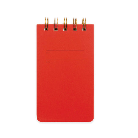 Warm red background with rectangular box in center with a place to title and date. Metal coil binding across the top. Inside has lined pages.