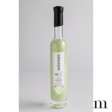 Salt & sage scented green colored milk bath packaged in a tall glass bottle.