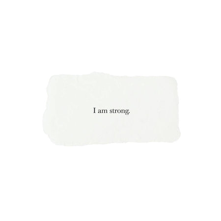 Ivory rectangle with torn edges and black text saying, “I am Strong”.