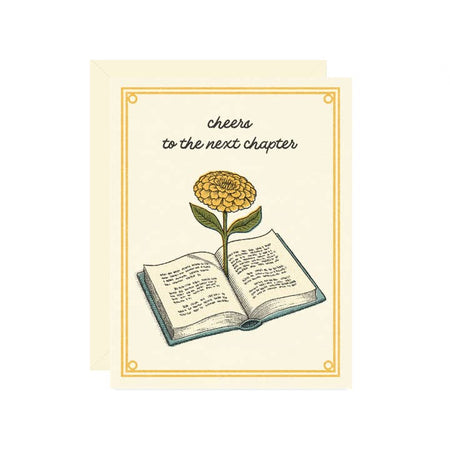 White card with image of an open book with a yellow flower coming out of the middle. Black text saying, “Cheers to the Next Chapter.” A white envelope is included.