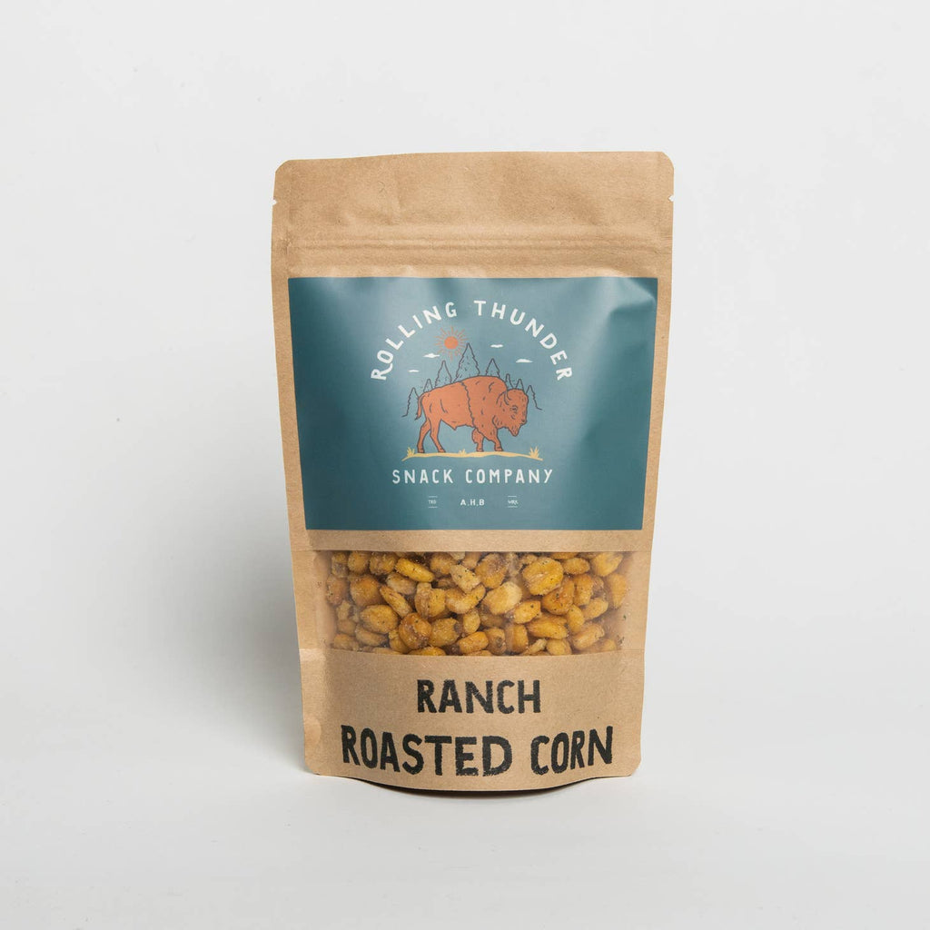 Tan bag with silver label with white text and black text saying, “Rolling Thunder Snack Company Ranch Roasted Corn”. Image of a brown buffalo in center of label. Clear strip across middle to see product inside. Brown roasted corn.