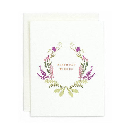 Ivory card with copper foil text saying, “Birthday Wishes”. Images of purple and pink floral wreath around the text. An ivory envelope is included.