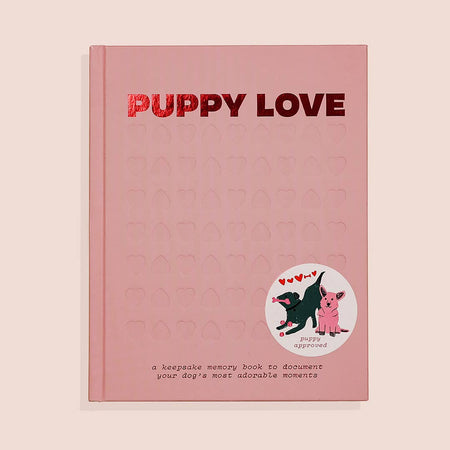 Pink cover with pink foil text saying, “Puppy Love”. Image of a black dog and a pink dog with floating red hearts.