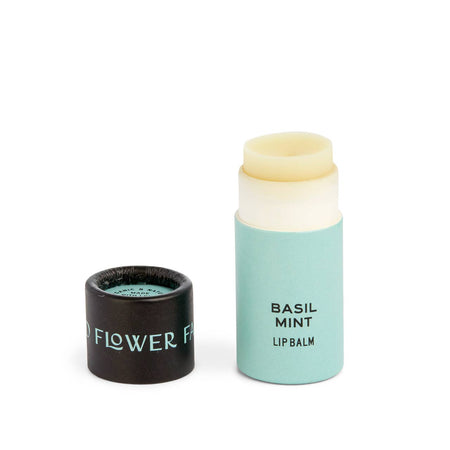 Mint green tube with black cover. Cover has mint green text saying, “Good Flower Farm”. Tube has black text saying, “Basil Mint Lip Balm”.  Balm is an ivory color.