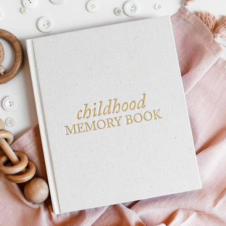 Ivory cover with gold embossed trim and gold text saying, “Childhood Memory Book” in center.