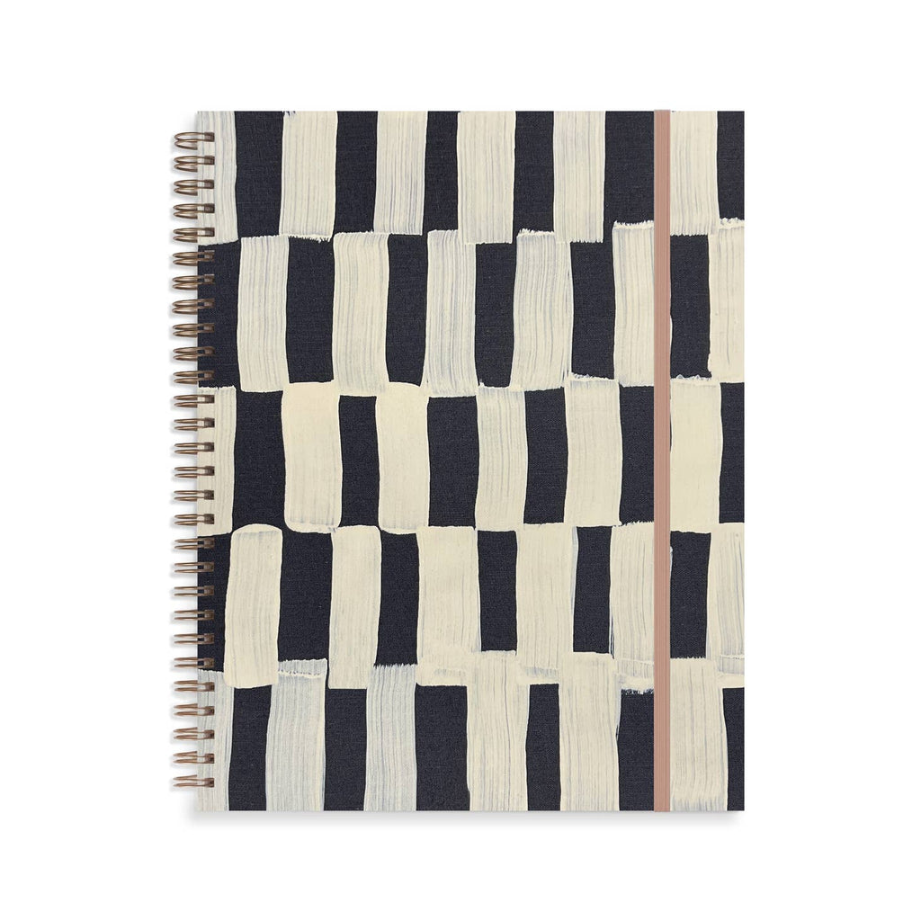 Notebook with ivory cover with black checker abstract pattern. Metal coil binding on left side. Tan elastic over right side.