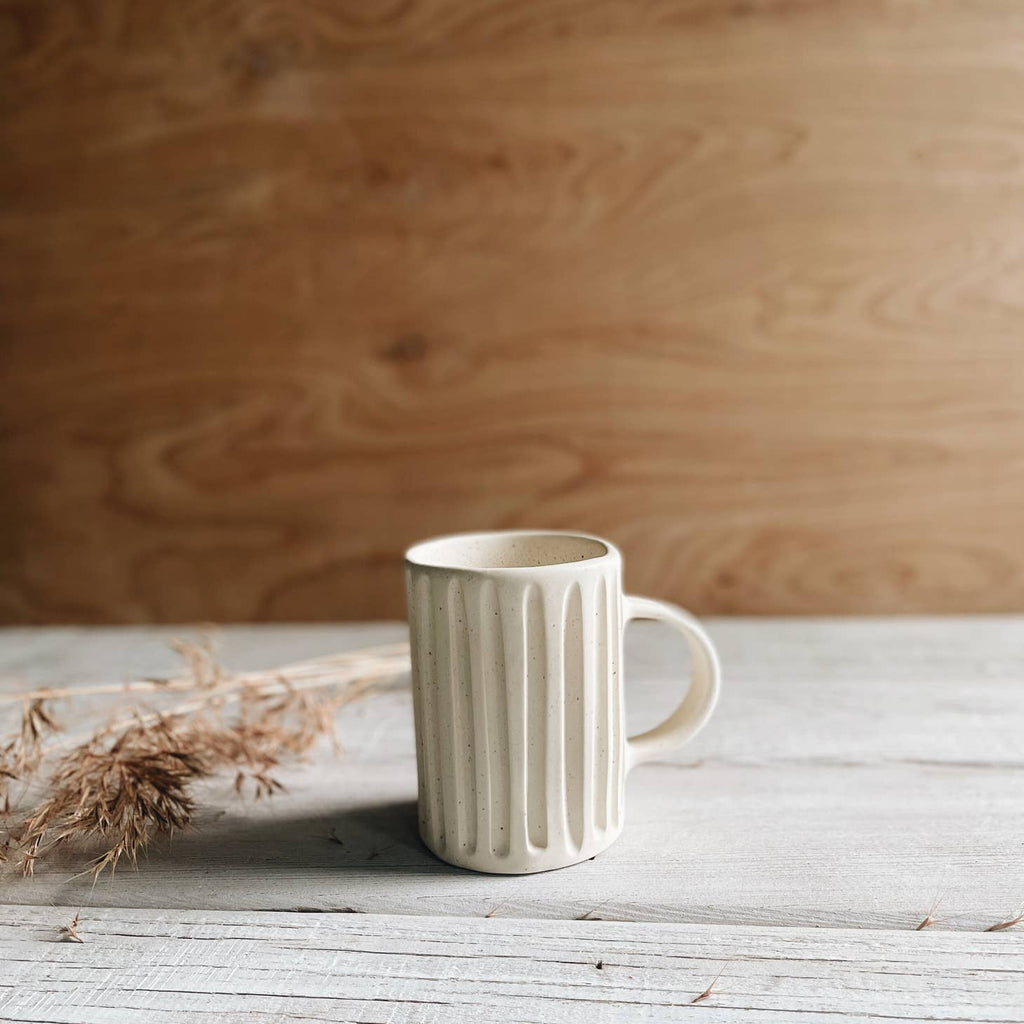 Ivory color mug with vertical lines carved into mug with ivory handle on side.