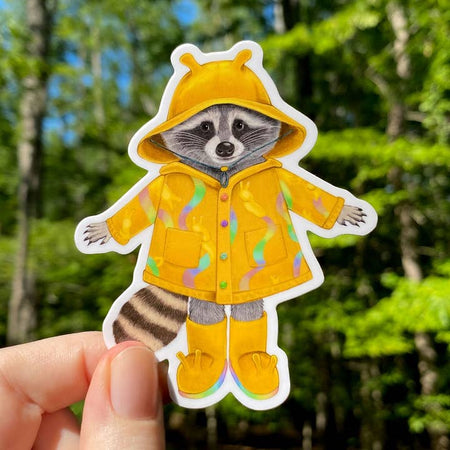 Sticker in the image of a raccoon wearing a yellow rain hat, yellow rain jacket and yellow rain boots.