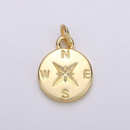 Gold charm in the image of a compass with “N, E, S, W” letters around it.