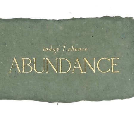 Green rectangle with torn edges and gold text saying, “Today I Choose Abundance”.