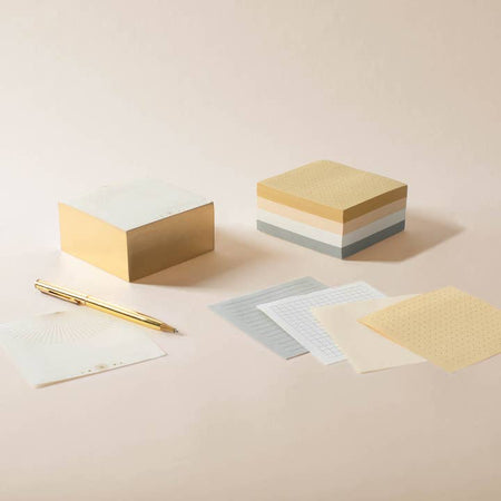 Square note pad with tan, cream, white and gray paper.