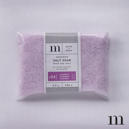Rectangular clear package with white and purple label. Black text saying, “Soothing Salt Soak with Sea Salt Lauren’s Lavender Garden”.
