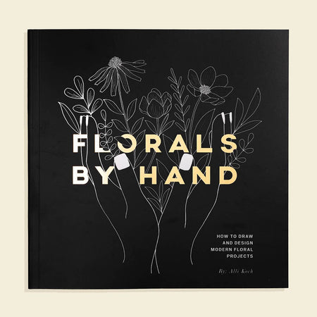 Black cover with white and yellow text saying, “Florals By Hand”. Images of the outline of two hands holding several kinds of flowers.