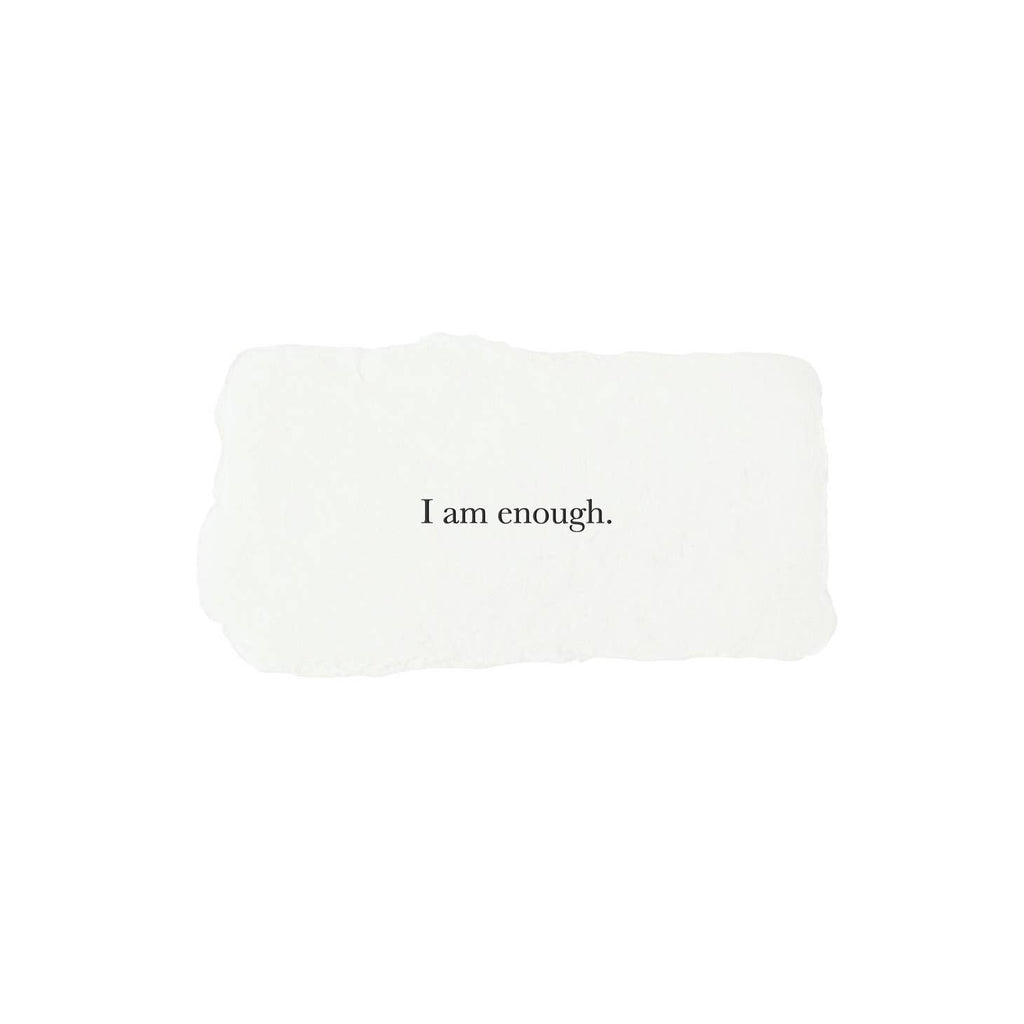 Ivory rectangle with torn edges and black text saying, “I am Enough”.