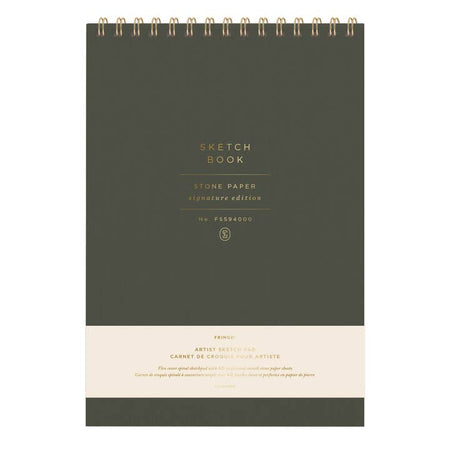 Olive green notebook with gold foil text saying, “Sketchbook Stone Paper Signature Edition” with gold coil binding across the top.