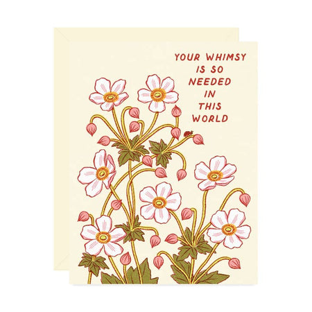 White card with images of pink and white flowers with pink text saying, “Your Whimsy is so Needed in this World”. A white envelope is included.
