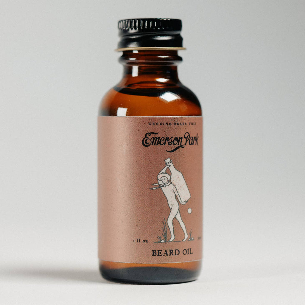 Brown glass bottle with black lid and red label. Black text saying, “Emerson Park Beard Oil”. Image of a man carrying a bottle on his back.