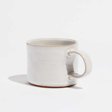 White ceramic mug with shiny glaze and handle on side.