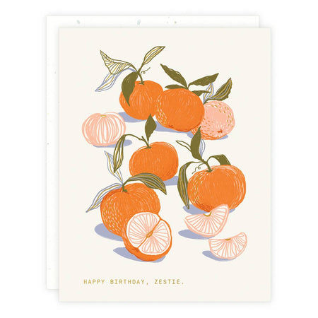 Ivory card with green text saying, “Happy Birthday, Zestie”. Images of oranges with green leaves. A white envelope is included.