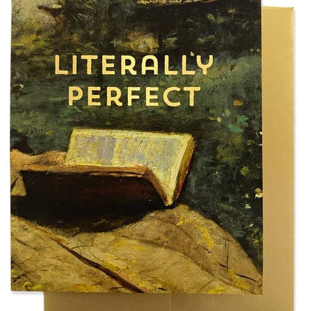 Greeting card with painting of a book and person on a ledge, yellow text saying, “Literally Perfect''. A gold foil envelope is included.