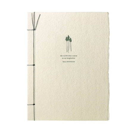 Off white notebook with torn edge cover. Green ribbon binding on left side. Image of green trees and green text saying, “The world is just a canvas to our imagination. Henry David Thoreau”.
