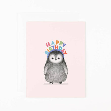 Light pink background with image of penguin wearing a happy birthday headband. Happy birthday letters are in various rainbow colors. A white envelope is included.