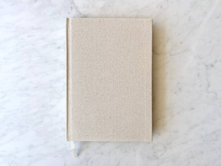 Notebook with off white linen cover and gold edging. 