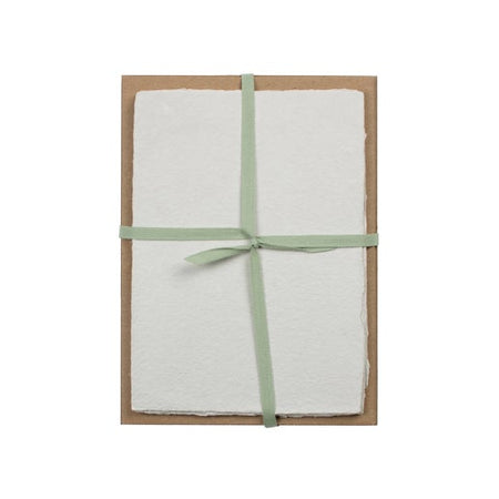 White paper with torn edge wrapped and tied with a light green ribbon.