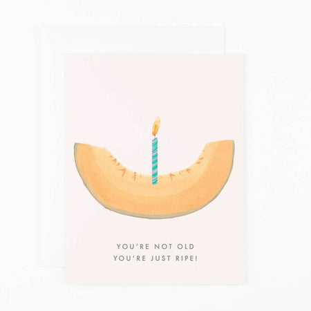 Light pink background with image of a slice of cantaloupe with a birthday candle stuck in middle. Gray text saying, “You’re Not Old You’re Just Ripe!” A white envelope is included.
