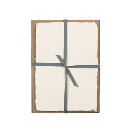 Off white paper with a torn edge wrapped and tied with a single blue ribbon.