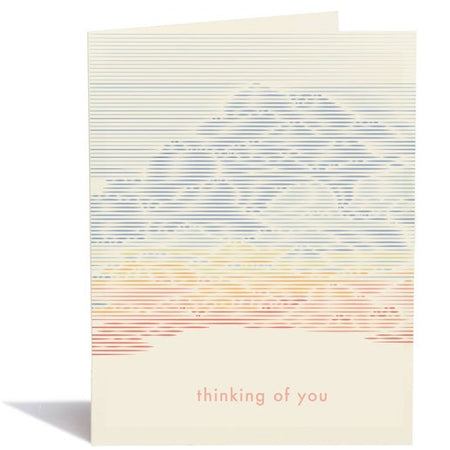 White card with muted image of mountains and valley in background. Pink text saying, “Thinking of You”. A white envelope is included.